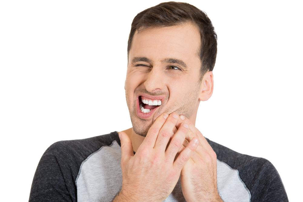 man in pain and holding his left cheek