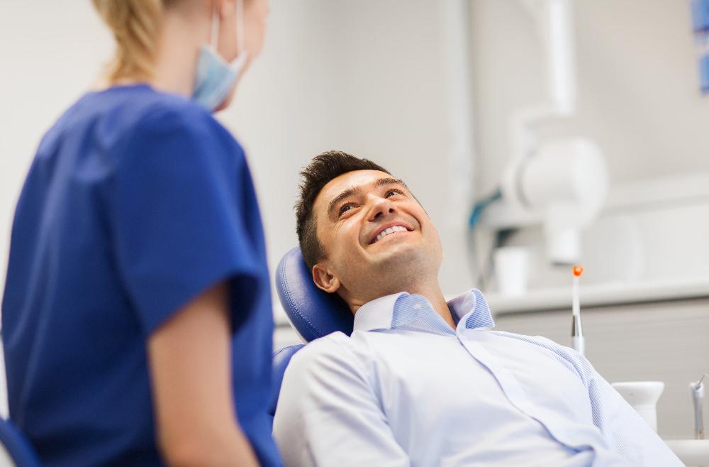 man smiling while sitting in a dental chair