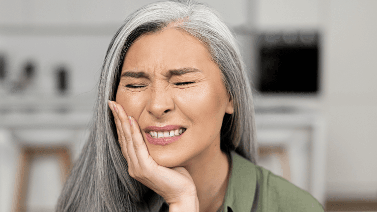 woman with silver hair color holding her right cheek